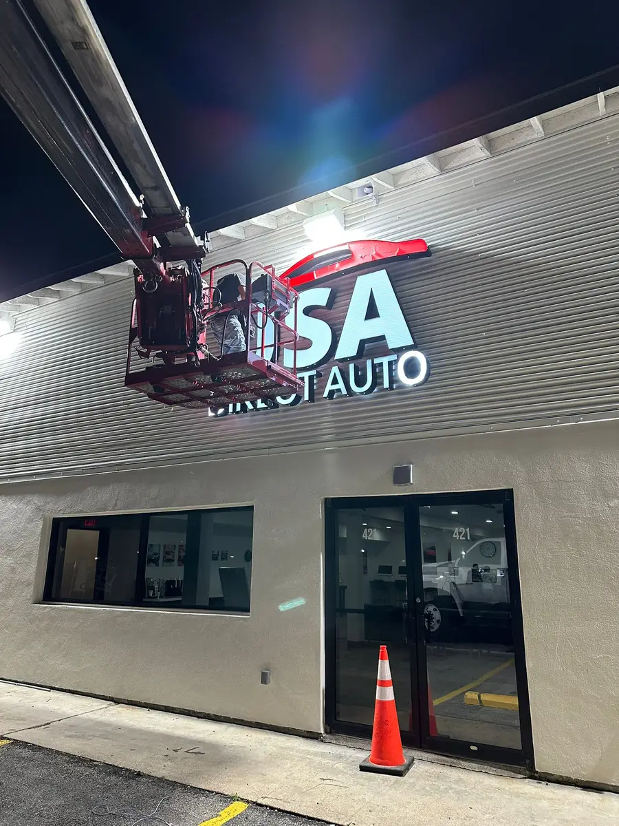 Uni Signs crew on a boom lift installing dimensional letter storefront sign at night in Katy, Texas