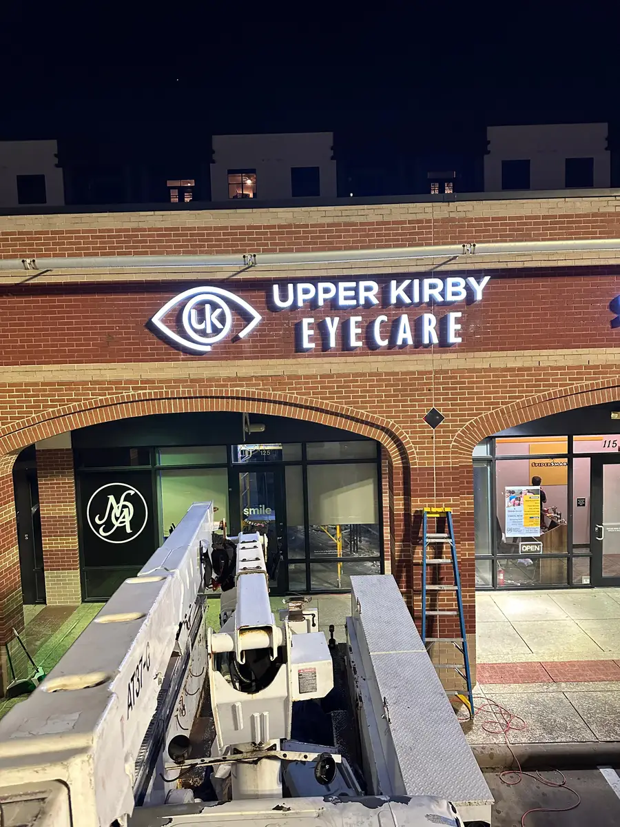 Illuminated dimensional storefront sign for Upper Kirby Eyecare medical office in Houston, Texas, installed at night